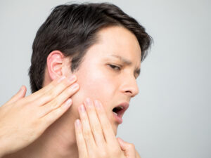 Young man experiencing TMJ pain