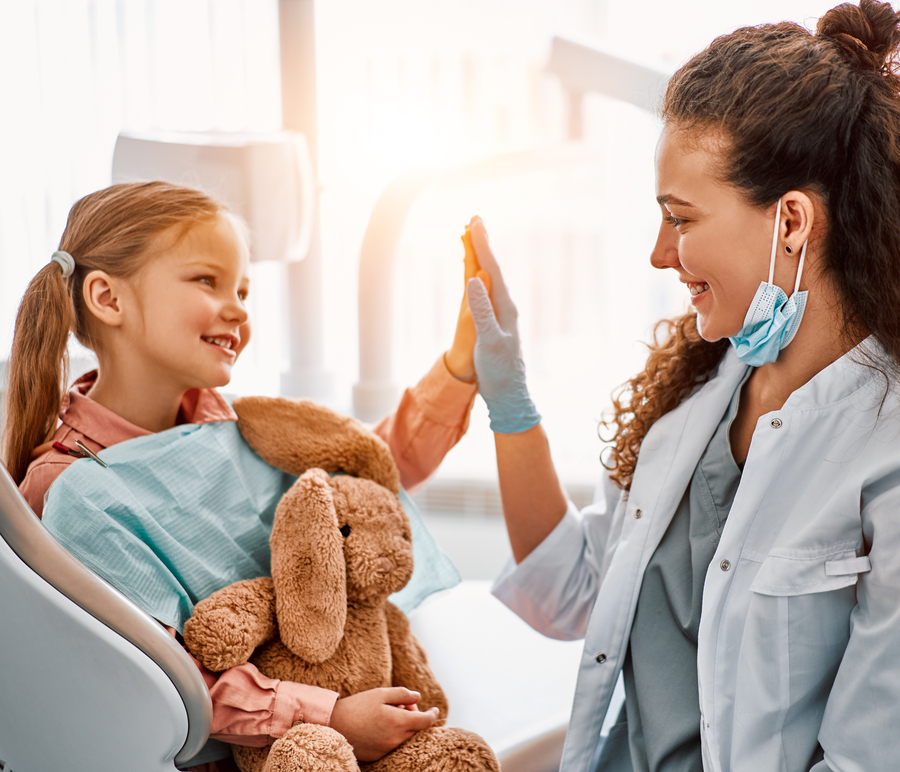 Little girl laughing and high-fiving her dentist