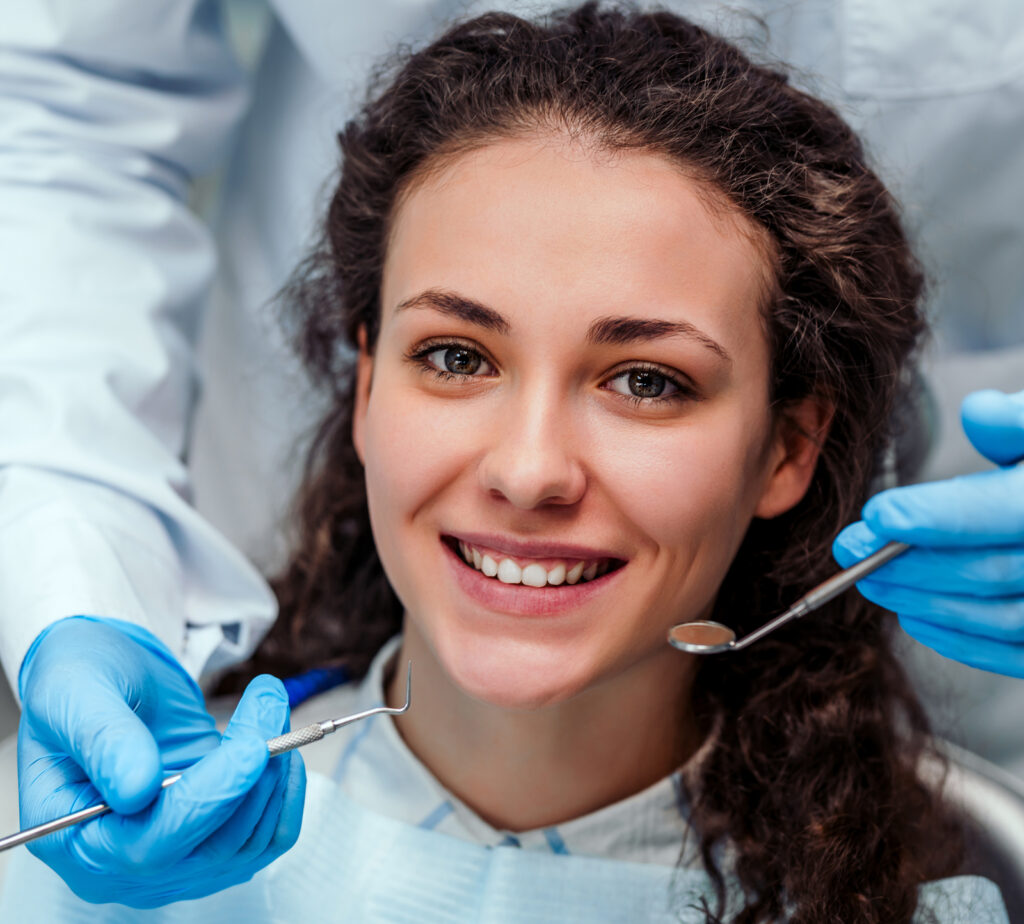 Dentist examining a girl's teeth with dental tools
