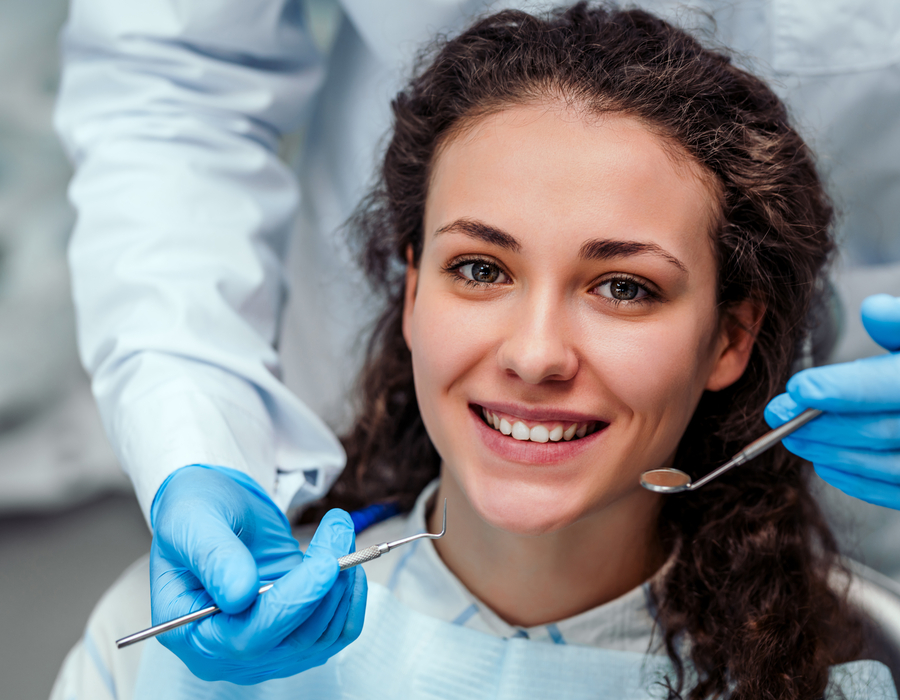 Dentist examining a girl's teeth with dental tools