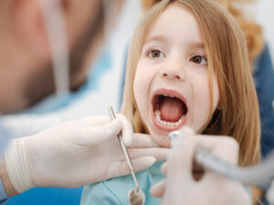 Girl displaying her healthy milk teeth at dental office