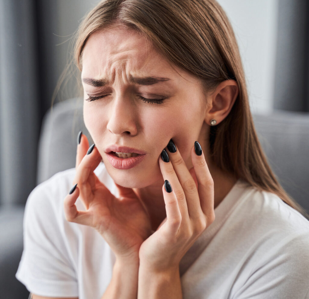 Girl holding her cheek in pain from toothache