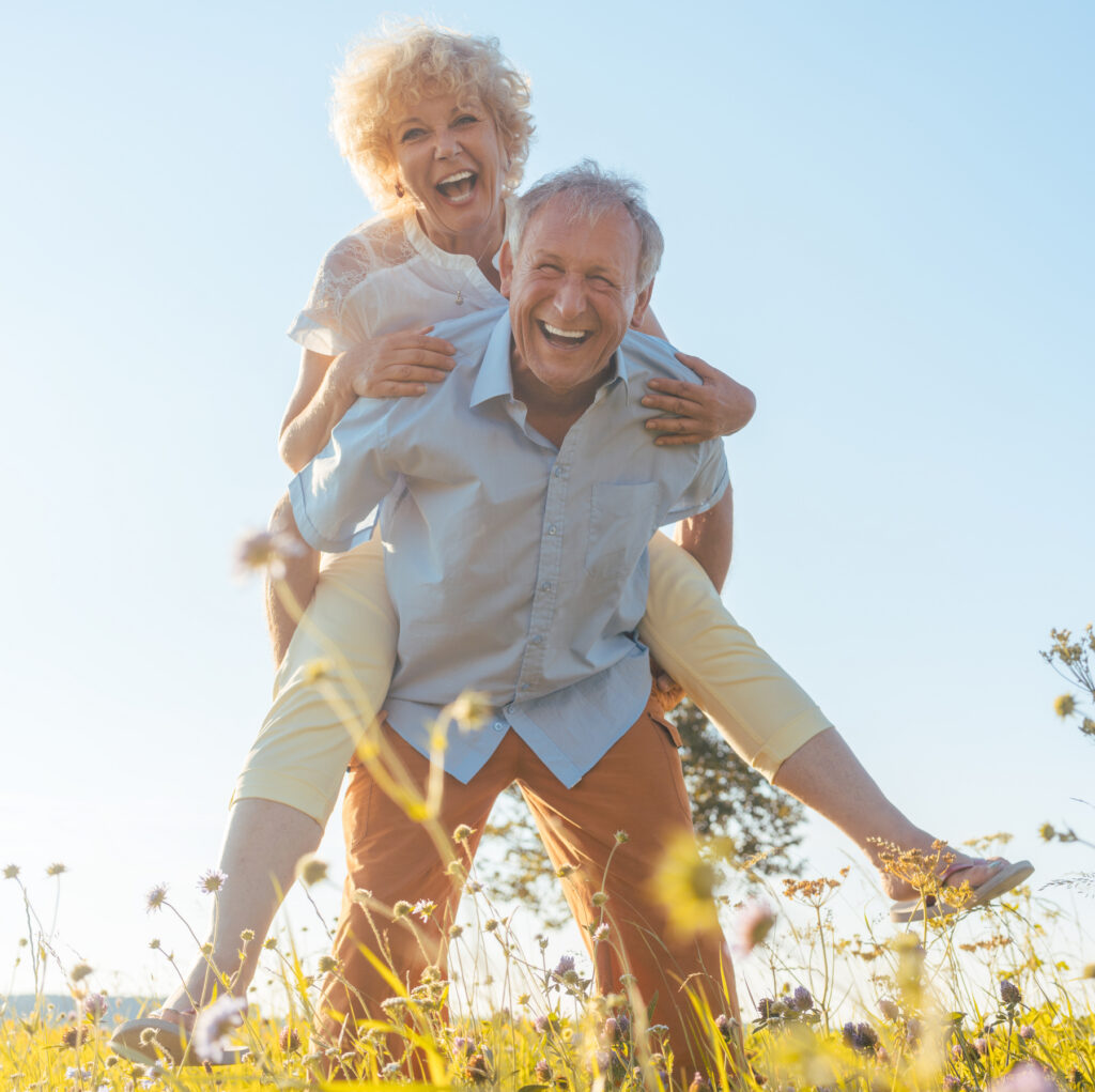 Happy senior man carrying his partner in the countryside