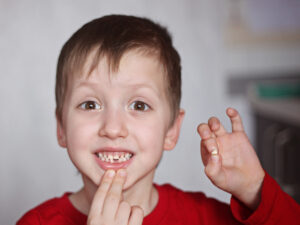 Cute boy showing his first lost milk tooth