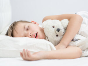 Little boy sleeping with toy bear and snoring