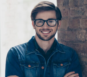 Bearded man smiling confidently near a brick wall