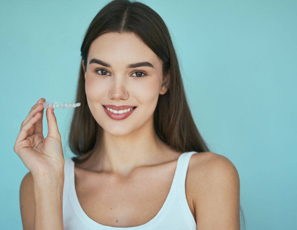 Woman smiling with clear aligner on blue background